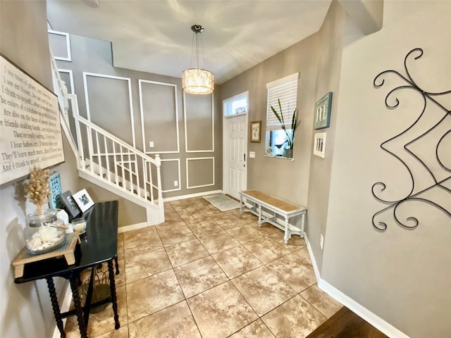 entryway featuring light tile patterned flooring, baseboards, and stairs