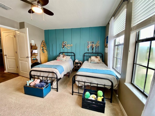 carpeted bedroom with a ceiling fan, visible vents, a textured ceiling, and baseboards