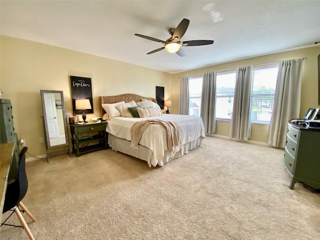 bedroom with ceiling fan, baseboards, and light colored carpet