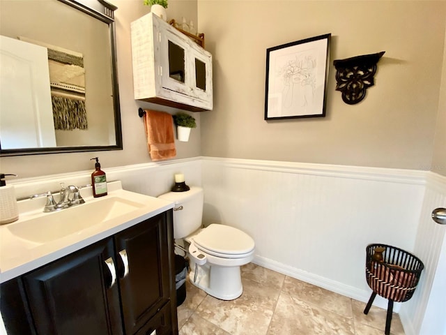 bathroom with a wainscoted wall, vanity, and toilet