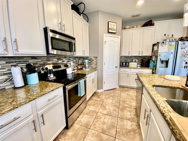 kitchen with light tile patterned floors, visible vents, decorative backsplash, appliances with stainless steel finishes, and white cabinetry