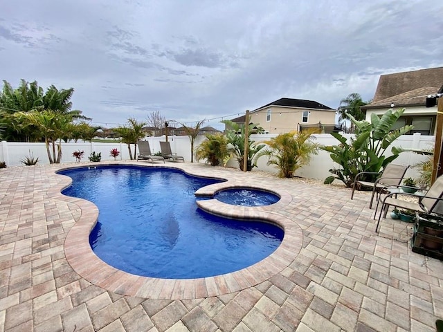 view of pool with a patio, a fenced backyard, and a pool with connected hot tub