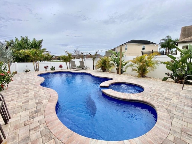 view of pool featuring a fenced backyard, a pool with connected hot tub, and a patio