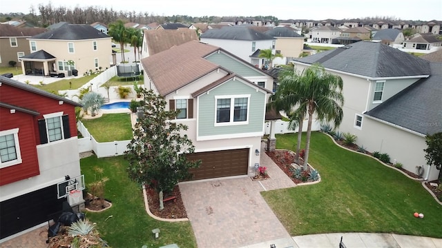 view of front of property with an attached garage, fence, decorative driveway, a residential view, and a front lawn