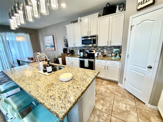 kitchen with appliances with stainless steel finishes, white cabinets, a sink, and tasteful backsplash