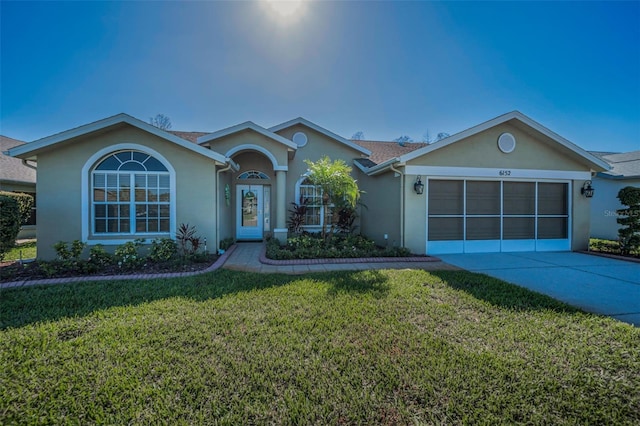 ranch-style home featuring an attached garage, concrete driveway, a front yard, and stucco siding