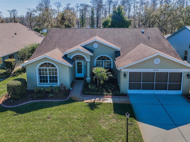 view of front of house with a garage, concrete driveway, roof with shingles, a front yard, and stucco siding