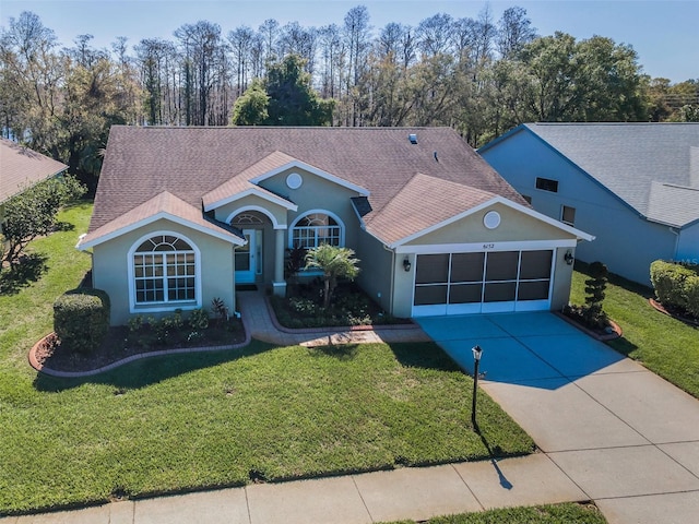 view of front facade featuring driveway, a front lawn, roof with shingles, and an attached garage