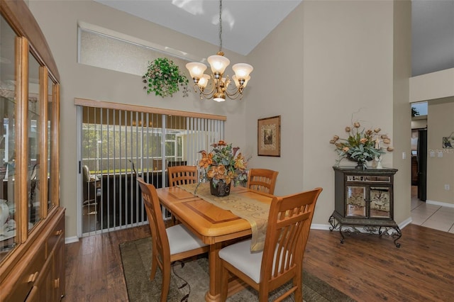 dining room featuring high vaulted ceiling, baseboards, an inviting chandelier, and wood finished floors