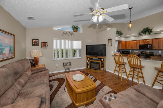 living area featuring lofted ceiling, a textured ceiling, visible vents, and wood finished floors