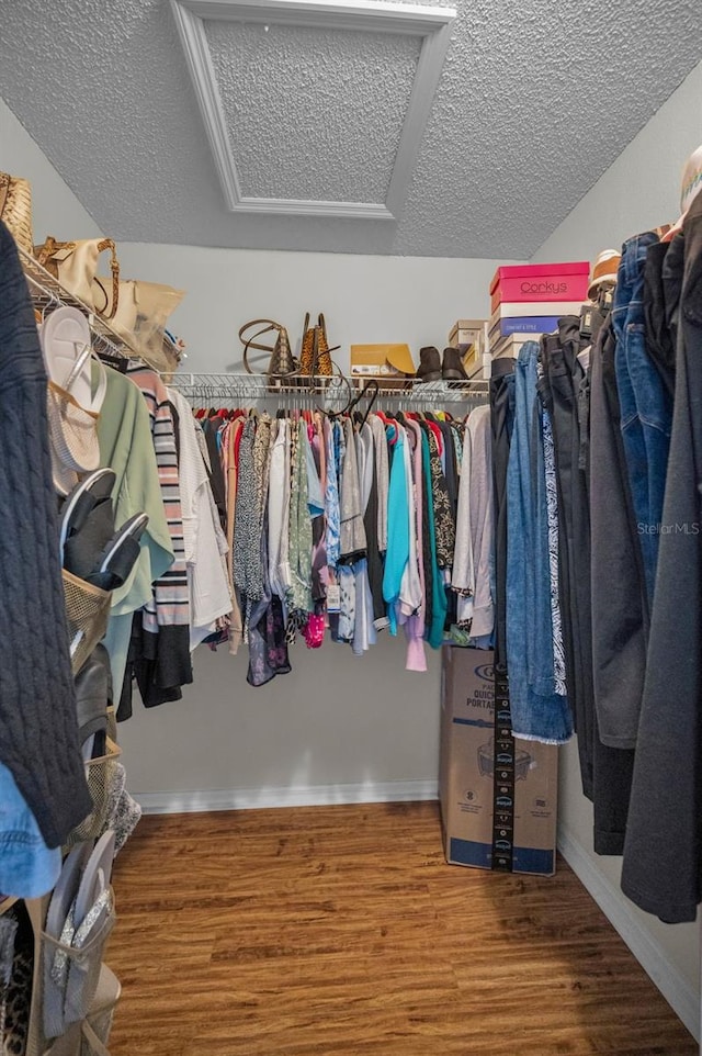 walk in closet with attic access and wood finished floors