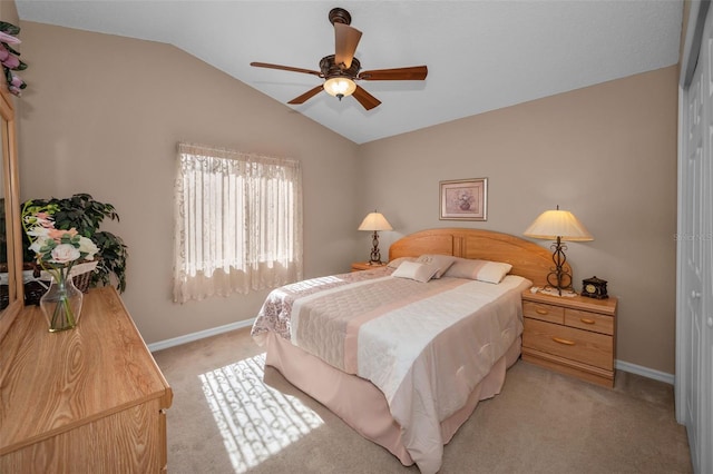 bedroom with lofted ceiling, a closet, light carpet, and baseboards