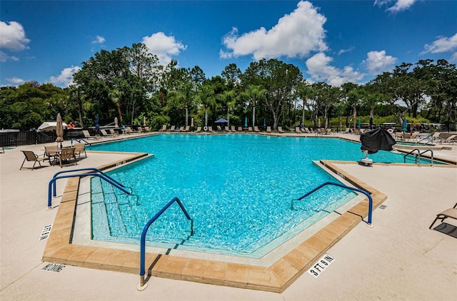 pool with a patio area and fence