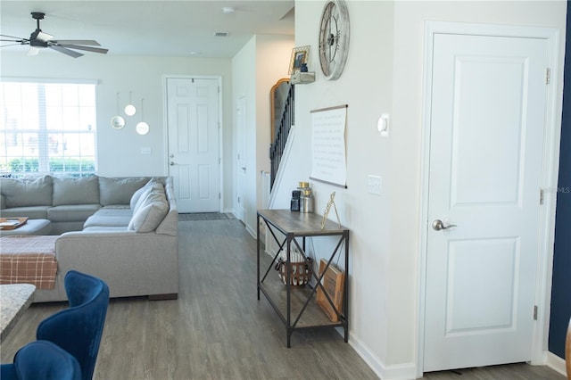 living room featuring wood finished floors, visible vents, a ceiling fan, stairs, and baseboards