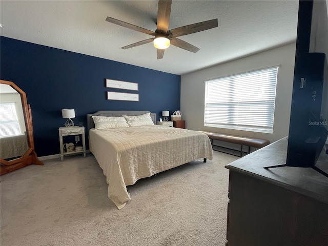 bedroom featuring light carpet, a textured ceiling, baseboards, and a ceiling fan