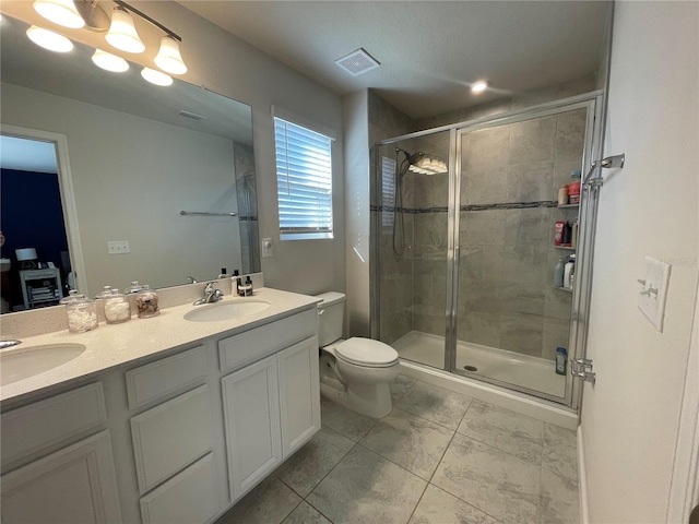 bathroom featuring toilet, a sink, visible vents, double vanity, and a stall shower