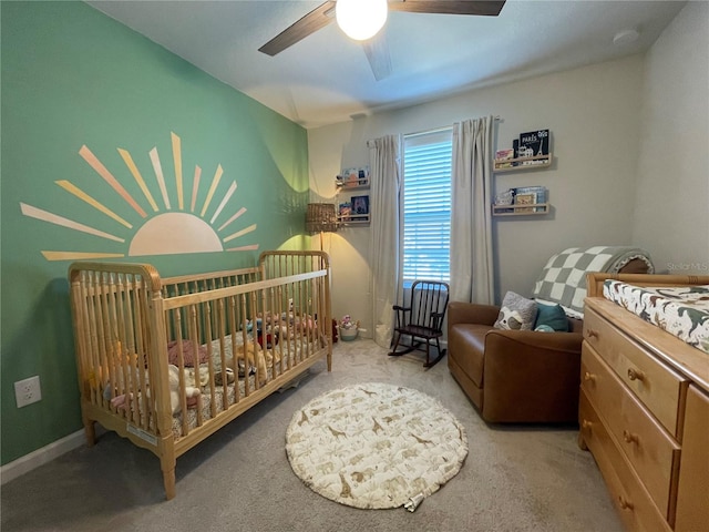 carpeted bedroom featuring a crib, ceiling fan, and baseboards