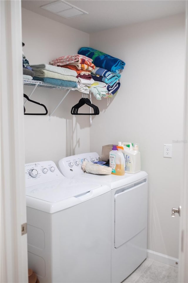 laundry area with laundry area, light tile patterned floors, baseboards, visible vents, and washer and dryer