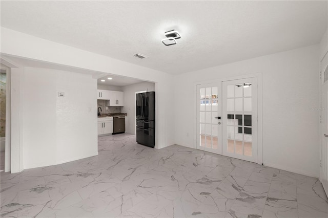 unfurnished room featuring a textured ceiling, marble finish floor, a sink, and visible vents