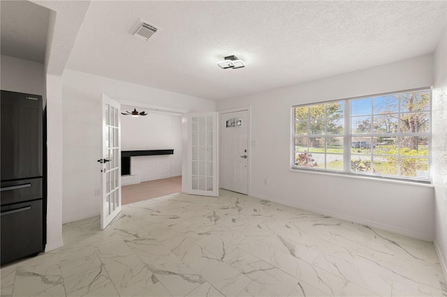 unfurnished room with baseboards, visible vents, marble finish floor, a textured ceiling, and french doors