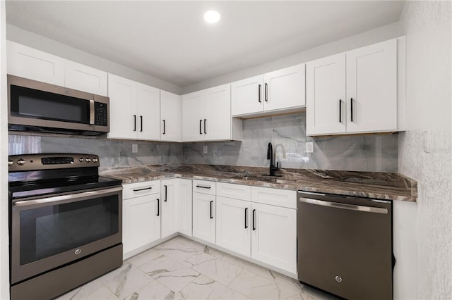 kitchen with marble finish floor, stainless steel appliances, dark stone countertops, and a sink