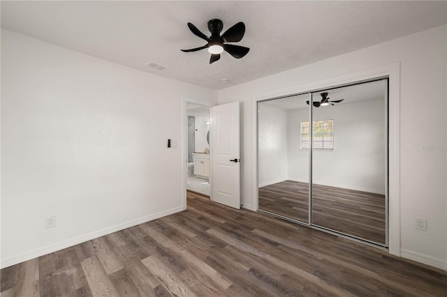 unfurnished bedroom featuring baseboards, visible vents, a ceiling fan, wood finished floors, and a closet