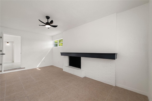 unfurnished living room featuring a brick fireplace, ceiling fan, and baseboards