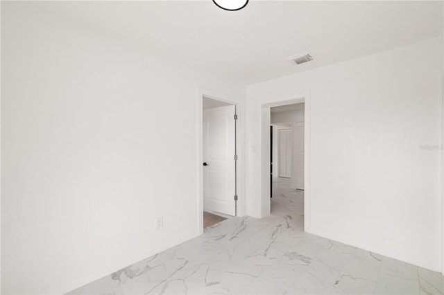 empty room with marble finish floor, visible vents, and baseboards