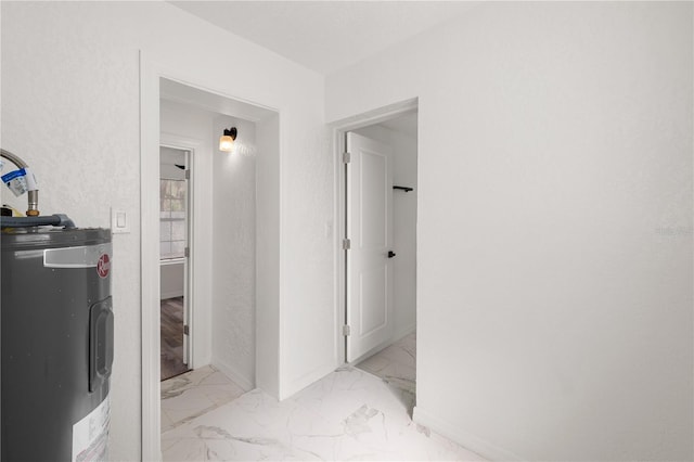 hall featuring marble finish floor, baseboards, and electric water heater