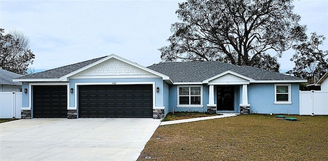 view of front of home featuring concrete driveway, an attached garage, a front yard, fence, and stone siding