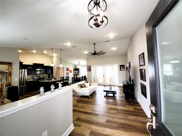 living room with dark wood finished floors, vaulted ceiling, and ceiling fan with notable chandelier