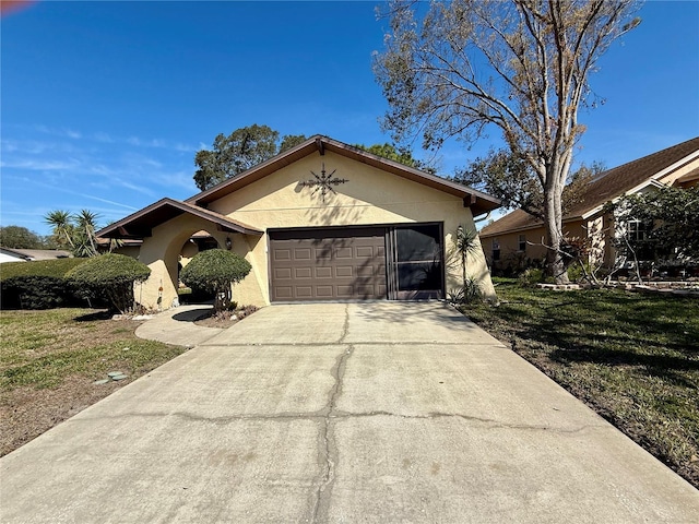 ranch-style home featuring a garage, concrete driveway, a front yard, and stucco siding