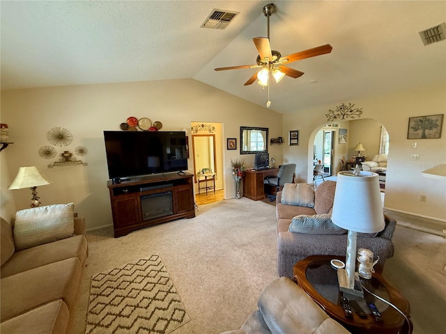 living room featuring lofted ceiling, ceiling fan, visible vents, and arched walkways