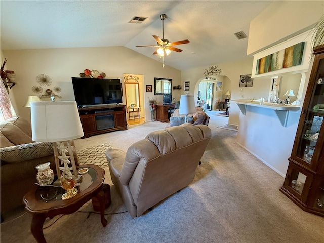 living area with arched walkways, light carpet, lofted ceiling, and visible vents