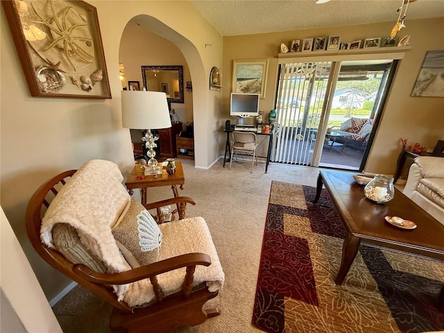 carpeted living room featuring lofted ceiling, arched walkways, a textured ceiling, and baseboards