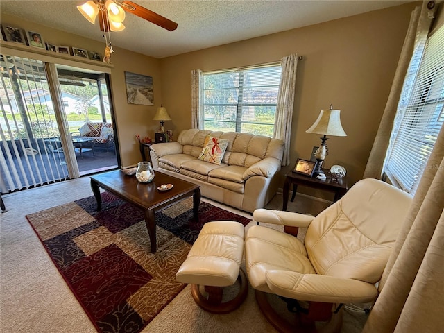 living area featuring a textured ceiling, ceiling fan, and carpet flooring