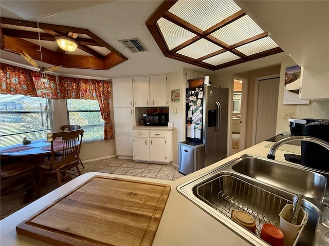 kitchen featuring black microwave, visible vents, white cabinetry, stainless steel refrigerator with ice dispenser, and a sink