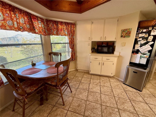 dining space featuring light tile patterned floors, a tray ceiling, and baseboards