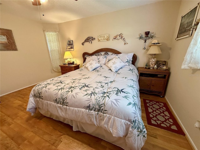 bedroom featuring a textured ceiling, baseboards, and wood finished floors