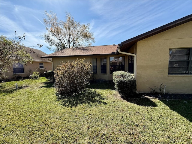 back of property with a yard and stucco siding