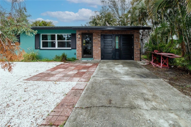 view of front of house with concrete driveway, brick siding, and stucco siding