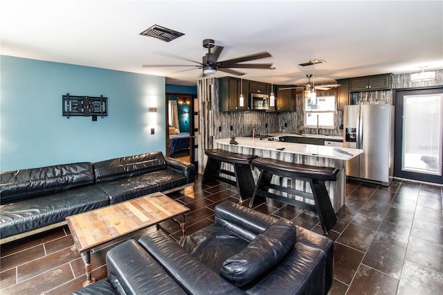 living area with visible vents and ceiling fan