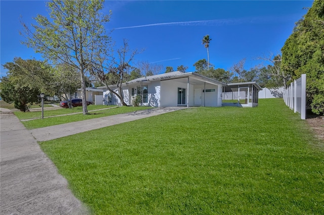 view of front of house with driveway, a sunroom, fence, and a front yard