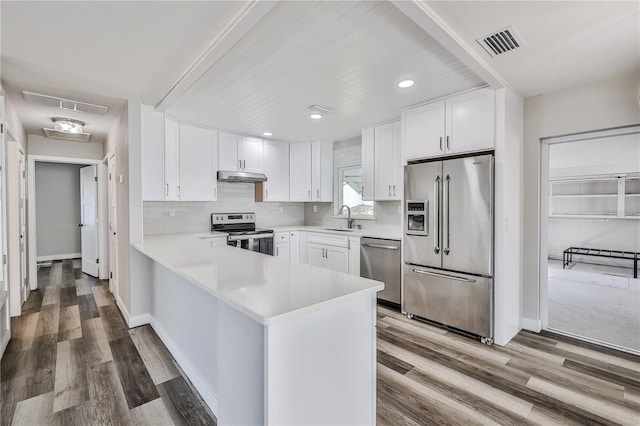 kitchen featuring under cabinet range hood, a sink, visible vents, light countertops, and appliances with stainless steel finishes