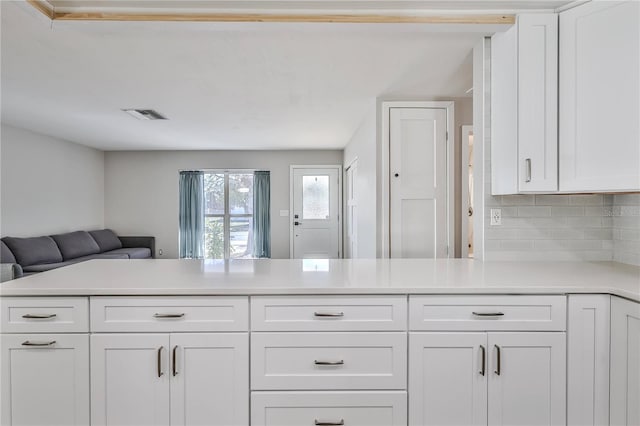 kitchen with a peninsula, visible vents, white cabinetry, open floor plan, and light countertops