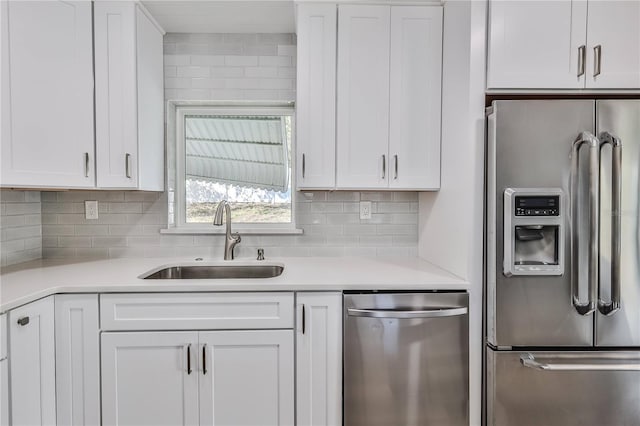 kitchen with appliances with stainless steel finishes, light countertops, white cabinets, and a sink