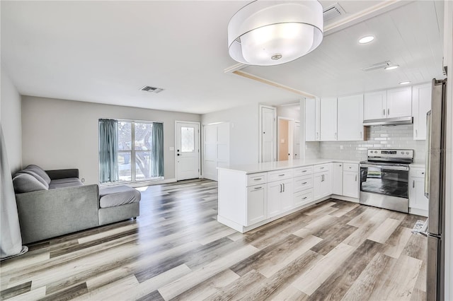 kitchen with under cabinet range hood, stainless steel appliances, a peninsula, visible vents, and open floor plan