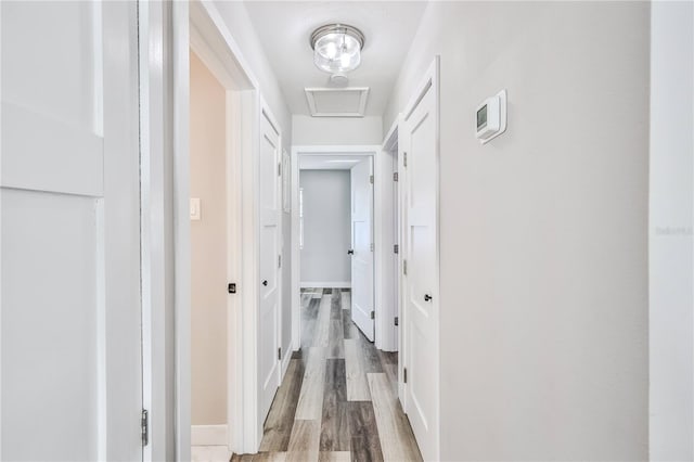 hall with attic access, baseboards, and wood finished floors