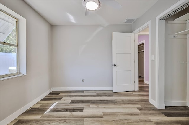 unfurnished bedroom featuring a ceiling fan, baseboards, visible vents, and wood finished floors