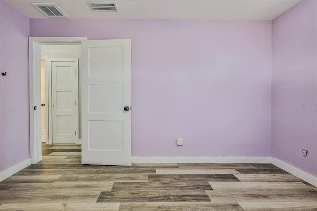 unfurnished room featuring visible vents, baseboards, and wood finished floors